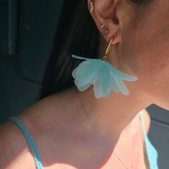 Close-up of a person wearing a light blue floral earring.