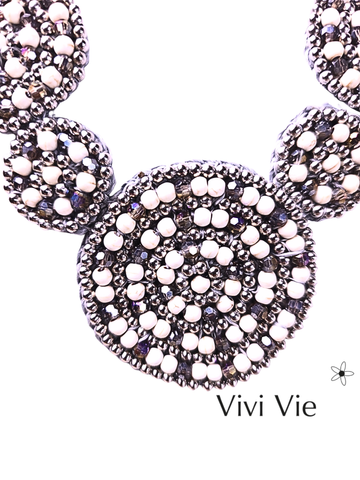 Beauiful and bold stament necklace with a neutral  palate and graduating circular  beaded design